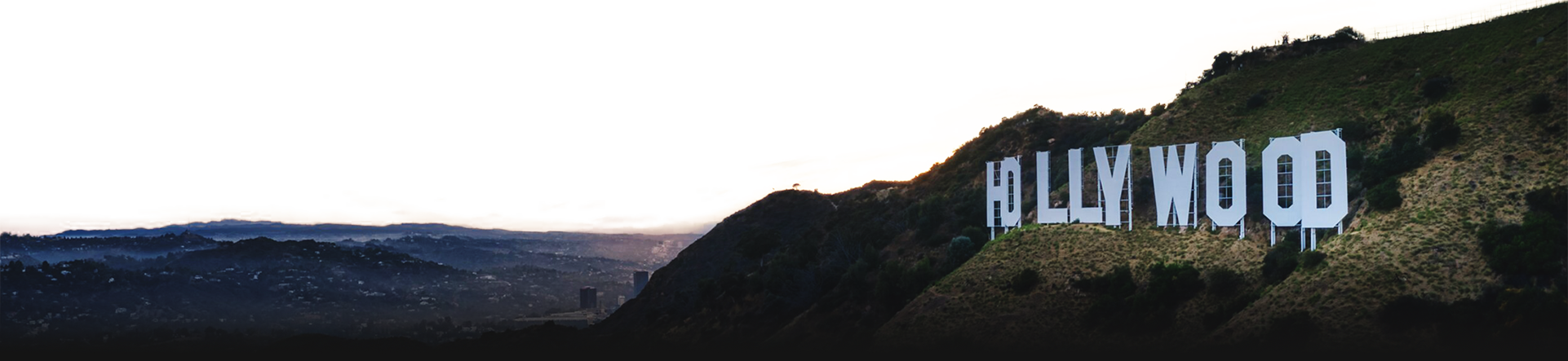 A scenic image of the Hollywood Sign on a hillside in Los Angeles, California, with a transparent background. The sign is illuminated, standing against a dark, mountainous landscape.